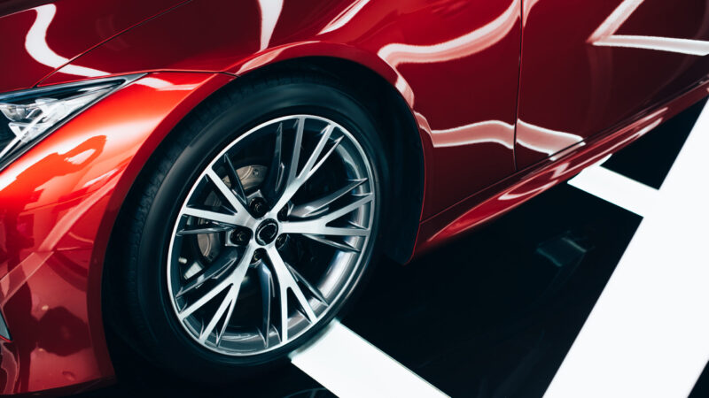shiny new red automobile with metallic wheel in car showroom